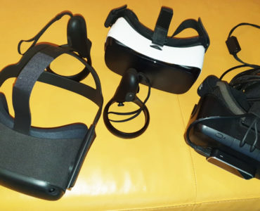Drei Virtual-Reality-Headsets und zwei Motion-Controller werden auf einer gelben Fläche präsentiert, wobei die Kabel neben einem Headset für eine beeindruckende 3D-Darstellung sichtbar sind.