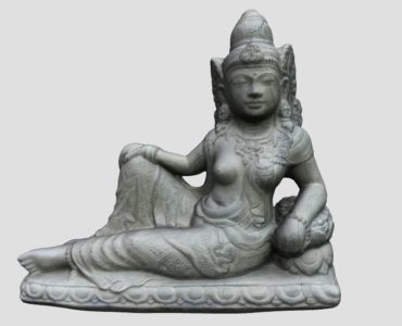 Steinstatue einer sitzenden Frau mit kunstvollem Schmuck und Kopfschmuck, die auf einem verzierten Sockel mit detaillierten Mustern ruht, vor einem schlichten hellen Hintergrund.